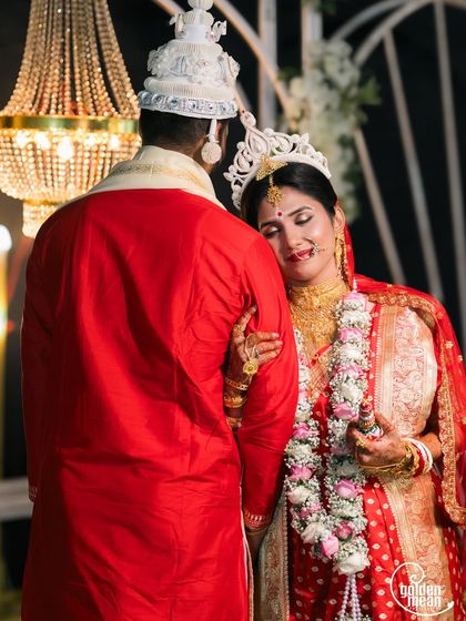 A tender moment between the bride and groom after their Bengali wedding ceremony, surrounded by beautiful decor.