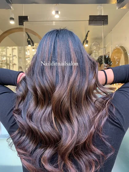 A perfect example of how highlights can add dimension to dark hair. We created these rich, caramel and light brown streaks, blending them seamlessly into the natural base color and styling them into soft waves to showcase the texture.