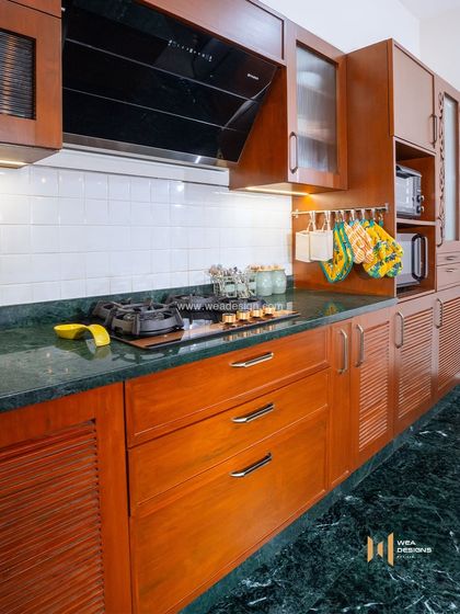 A close-up of the veneer kitchen cabinetry, showing the rich texture of the wood and the beautiful green marble flooring.