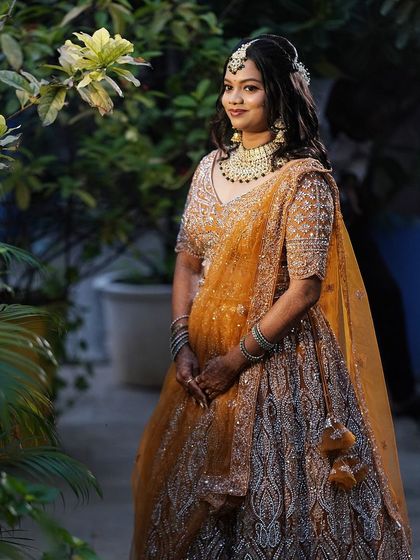 A gorgeous bride in a mustard and silver lehenga. The outdoor setting highlights the fresh and glowing makeup I created for her reception.