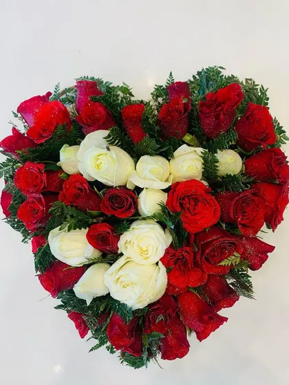 A heart-shaped floral arrangement made with fresh red and white roses. This is a perfect centerpiece or gift for Valentine's Day, anniversaries, or to express your love.