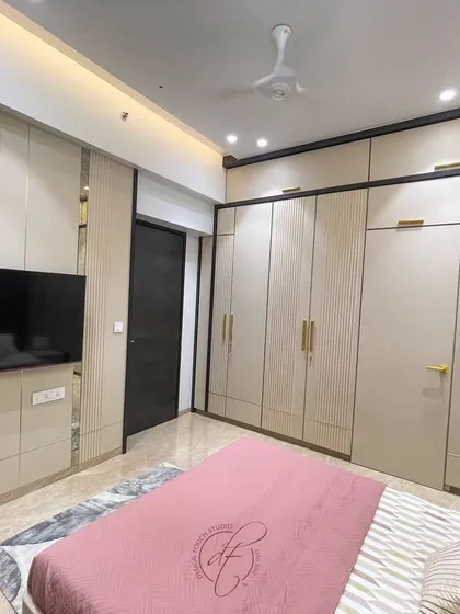 This shot showcases the full wall of custom wardrobes with elegant gold handles. The design provides ample storage while serving as a stylish architectural element in the room.