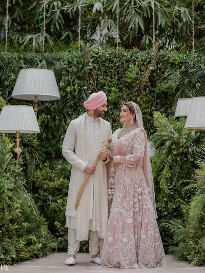 An elegant portrait of a Sikh couple during their Anand Karaj ceremony, set against a lush green backdrop.