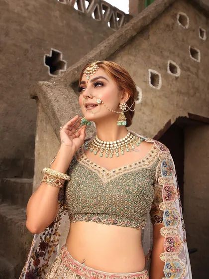 This bride is wearing a beautiful pastel green lehenga with a floral embroidered dupatta. It's a fresh, modern, and elegant choice, paired perfectly with a simple Kundan necklace.