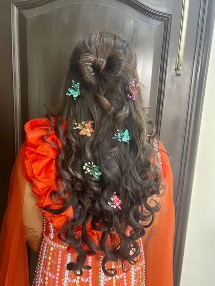 A fun and unique hairstyle for a Mehendi or Sangeet event, featuring long curls adorned with colorful butterfly clips.