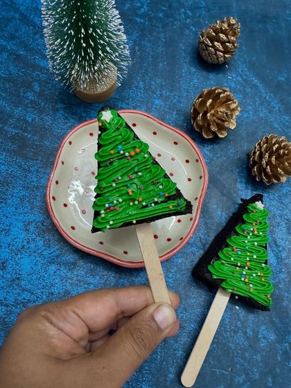 A simple and fun Christmas treat! These are my brownie cakesicles, shaped and decorated like little Christmas trees with green frosting and sprinkles.