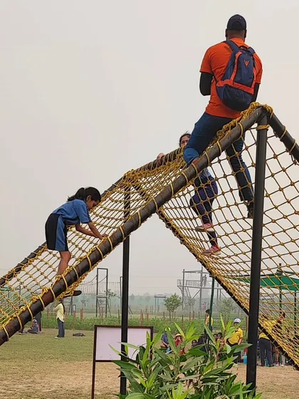 A student climbs a commando net at the adventure camp. Activities like these are designed to build physical strength, courage, and problem-solving skills under the supervision of trained instructors.