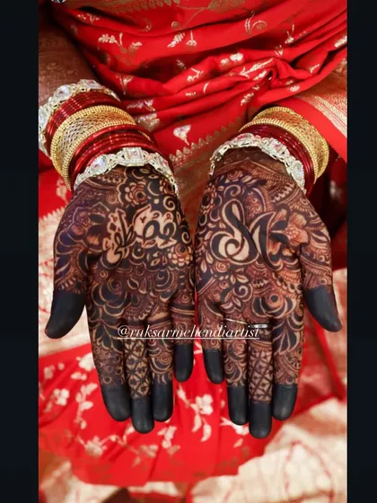 The rich, dark stain on this bridal design highlights the couple's initials, 'S' and 'M', hidden within the intricate patterns.