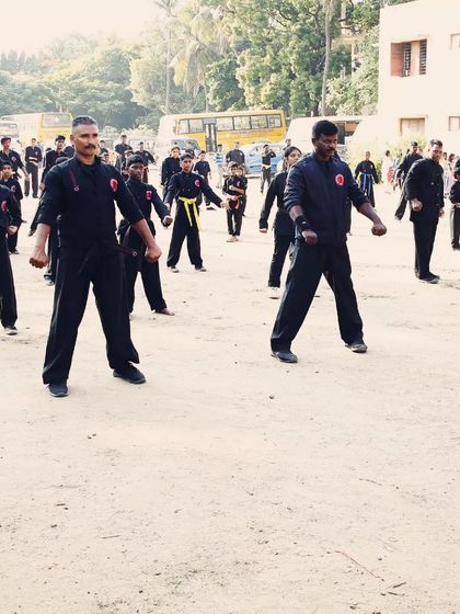 Students of different belt levels (yellow and black belts visible) practicing their stances together during a combined belt test.