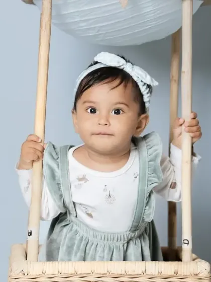 A sweet baby girl peeking out from the hot air balloon basket.