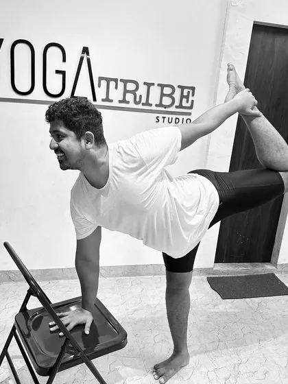 A black and white shot of the same pose. The chair is a simple but powerful tool for learning alignment and finding stability in challenging balancing poses.