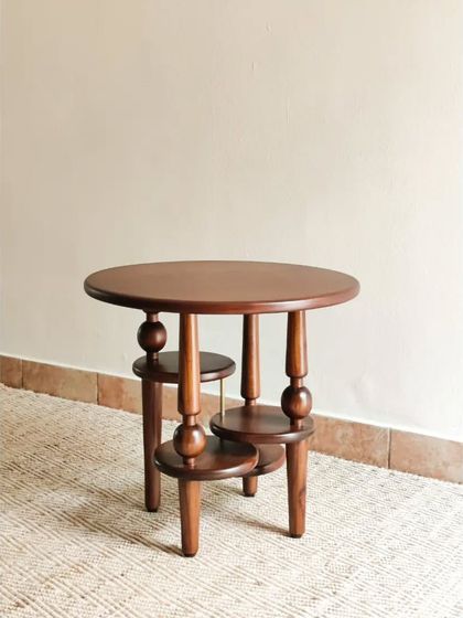 The Vibhinna Side Table is an artfully designed statement piece. Its unique multi-tiered structure and turned wood details create a sculptural form that is both a functional table and a piece of art.