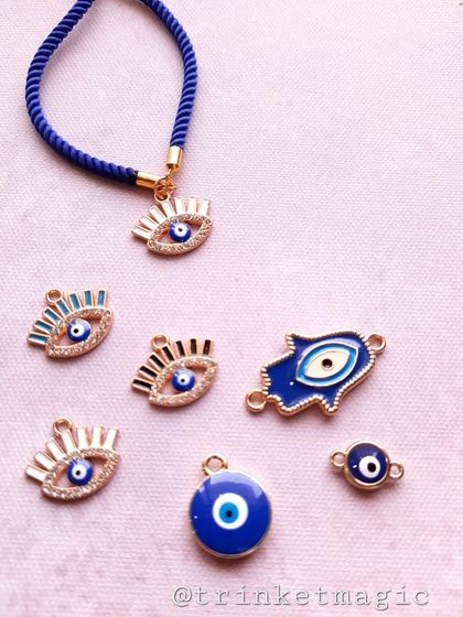 A collection of evil eye charms and a finished adjustable cord bracelet. This image shows the variety of protective charms you can choose for your custom Rakhi.