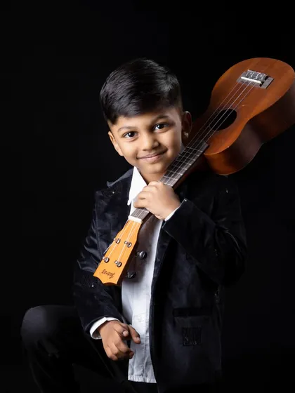 A confident portrait of the 5-year-old boy holding his ukulele over his shoulder.
