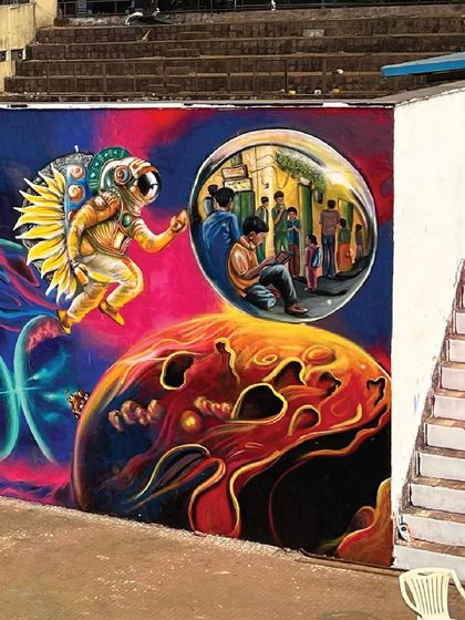 One side of the IIT Bombay mural, featuring an astronaut with sun-like wings looking into a bubble that reflects a scene of learning and community. It’s about looking outward to space and inward to our roots.