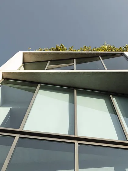 An upward-looking view of our studio's facade. The design features clean lines, a raw concrete finish, and a rooftop garden, reflecting our core architectural principles of materiality, clarity, and integration with nature.