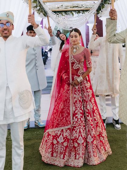 The bride's grand entrance under the phoolon ki chadar. Her makeup is fresh and radiant, making her glow as she walks down the aisle.