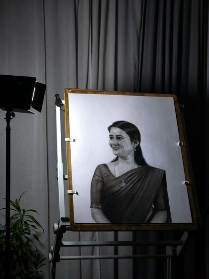 The finished portrait under a studio light, which highlights the deep blacks and soft grays achieved with charcoal and graphite.