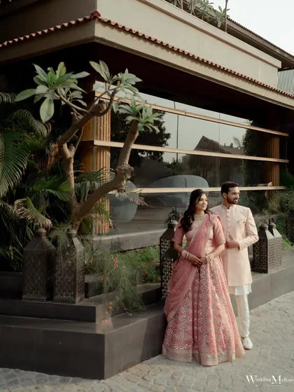 An elegant portrait of the couple at their engagement venue. The modern architecture and lush greenery provide a beautiful backdrop for this stylish shot.