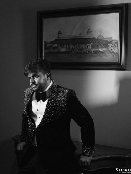 A classic black and white portrait of the groom, Harshit, in his tuxedo, looking dapper and thoughtful.