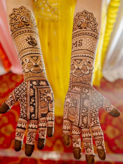 This bridal mehendi is full of auspicious symbols, including Lord Ganesha, elephants, and kalash motifs. The couple's initials "MS" are also personalized on the arm.