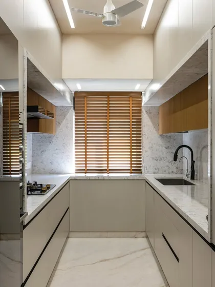 This U-shaped kitchen is a study in symmetry and calm. The neutral palette, clean lines, and warm wooden blinds create a serene and balanced space that feels both modern and timeless.