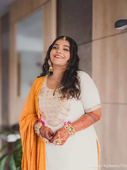 A radiant bride in a simple white and yellow outfit for her Haldi. The makeup is minimal with a pop of blue eyeliner for a fun twist.