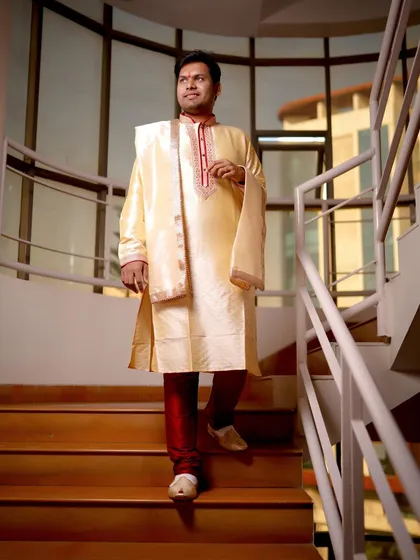 A classic portrait of the groom in his traditional Indian attire. He is captured walking down a staircase, looking elegant and ready for the ceremony.