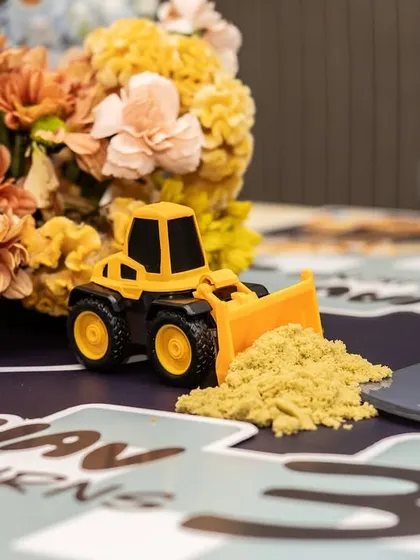 Another angle on the playful table decor, with a toy bulldozer pushing a pile of "dirt" next to a bouquet of yellow flowers.