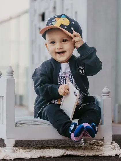 A playful moment captured as the baby tips his cap towards the camera during his stylish pre-birthday photoshoot.