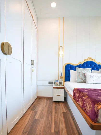 This view shows the custom white wardrobe with unique gold handles, designed to complement the royal blue and gold theme of the master bedroom.