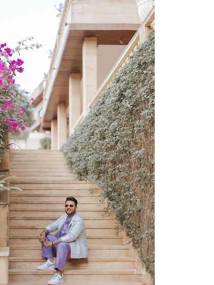 A groom looking stylish on his wedding day, wearing custom sneakers designed to match his lavender and blue outfit.