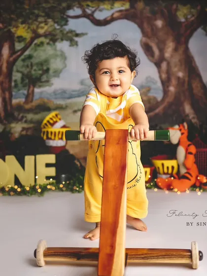 This little boy is ready for his first steps, using a walker during his Winnie the Pooh themed first birthday shoot.