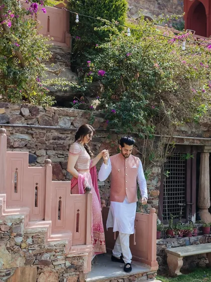 A couple descends a rustic staircase at Fort Neemrana, hand-in-hand, a moment of quiet elegance.