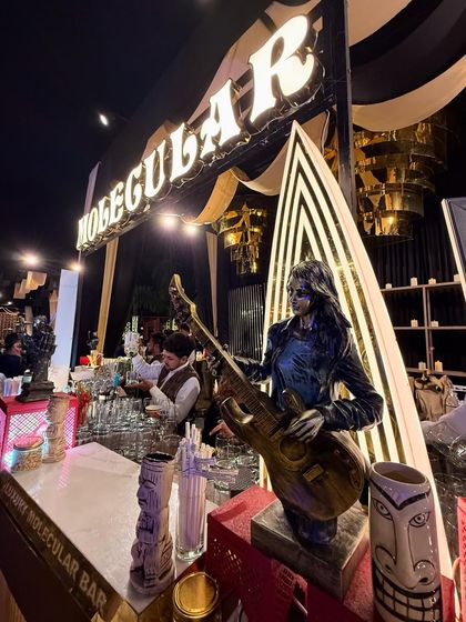 A close-up of our Art Deco inspired bar, featuring bold black-and-white patterns, musician statues, and quirky tiki-style mugs.