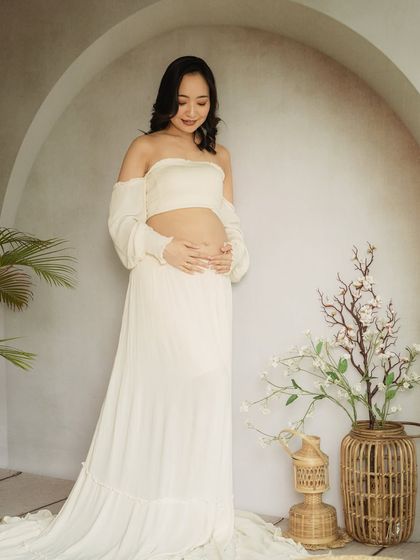 A minimalist and modern solo portrait. The simple white two-piece outfit and clean background create a fresh, contemporary look.