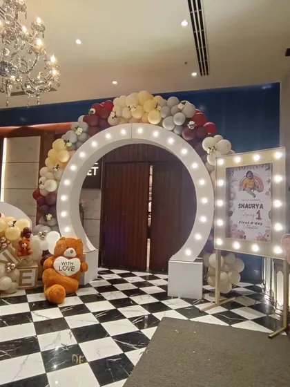 We make entrances that wow your guests. For this first birthday party, we designed a grand welcome area with a large circular arch fitted with marquee lights, a custom photo frame, and a theme of teddy bears and balloons.