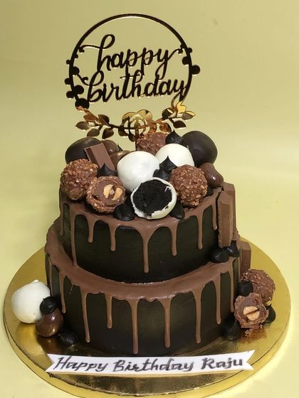 A two-tiered chocolate drip cake perfect for a birthday. This decadent creation is loaded with Ferrero Rocher, Oreo truffles, and chocolate bars for the ultimate indulgence.