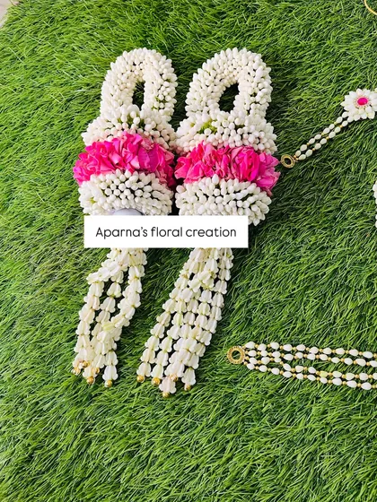 A close-up of fresh floral bajuband made with white buds and accented with pink flowers. These are designed to be worn on the upper arms.