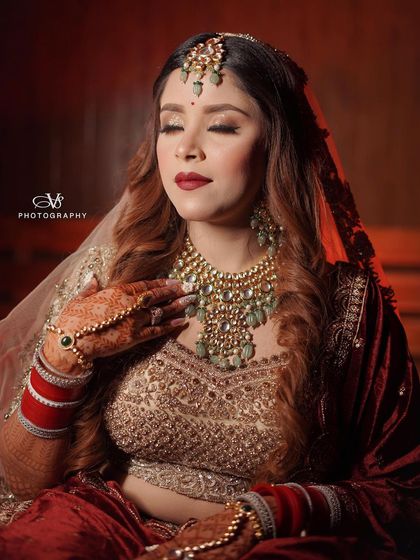 A serene and elegant bridal portrait, capturing the bride with her eyes closed, highlighting the rich details of her velvet lehenga and jewelry.