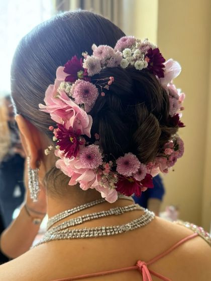 This bridal bun is adorned with a beautiful arrangement of pink and burgundy chrysanthemums and baby's breath, creating a full and vibrant floral crown.