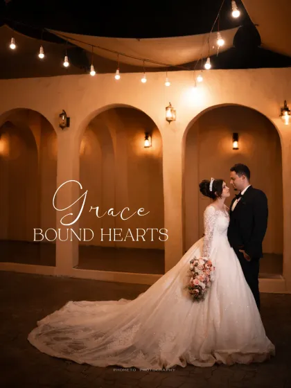 'Grace Bound Hearts'. A stunning wide shot showcasing the bride's beautiful gown and the romantic ambiance of the venue.