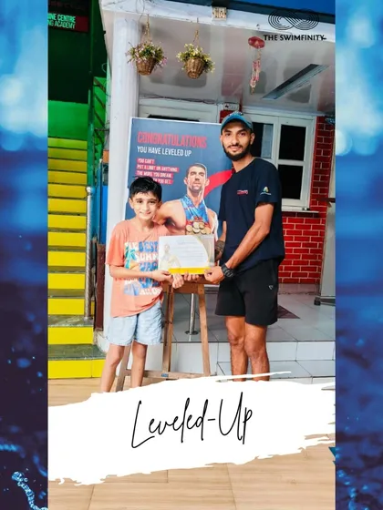 Achievement unlocked! A young swimmer proudly receives his certificate for leveling up in June. Every milestone is a victory.