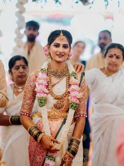 My beautiful client-turned-family, Chethana, looks timeless in this white and pink Kanchipuram saree. I designed a heavily handcrafted bridal blouse with intricate zardozi work to complement the saree's elegance for her special day.