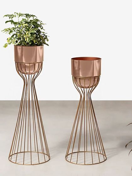 These artistic metal planters feature a sleek, sculptural wire base in a rose gold finish. They elevate your plants, turning them into a modern design statement for any corner of your home.