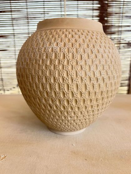 This is one of my favorite surface decoration techniques. I apply a layer of white slip over the pot and then carve through it to create these intricate, dotted patterns.
