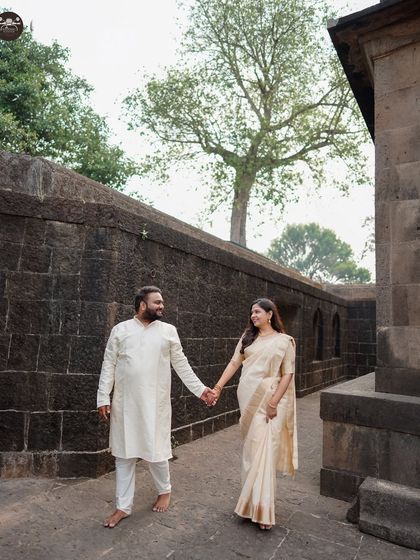 A couple in beautiful traditional attire walking through the stone corridors of a heritage site. This candid shot captures a simple, elegant moment.