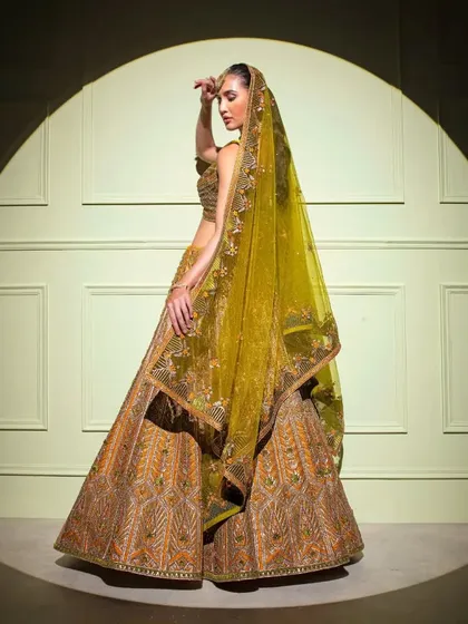 A side profile of the regal gold bridal lehenga, showcasing the volume of the skirt and the intricate detailing on the dupatta.