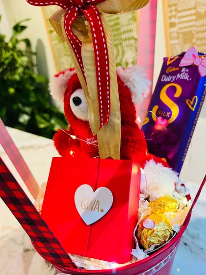 A close-up of the basket, showing the Giva jewelry box, Dairy Milk Silk, and a cuddly red teddy bear.