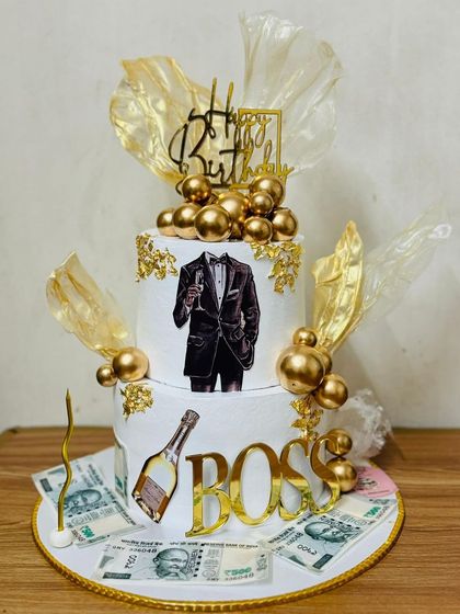 A grand two-tier "Boss" themed cake with money and gold accents.
